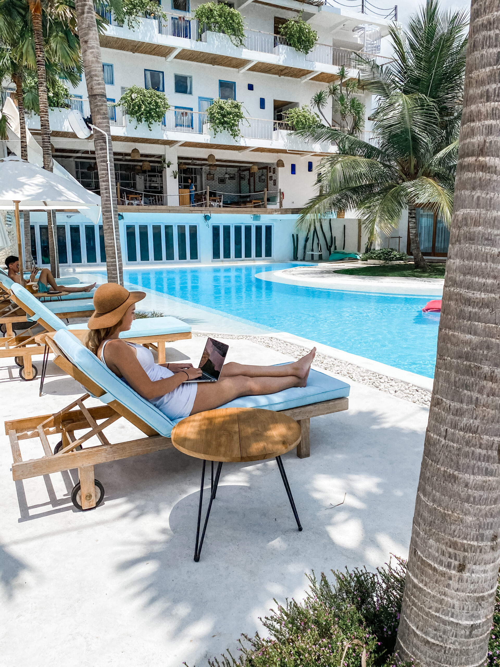 Digital nomad working on a laptop by the pool